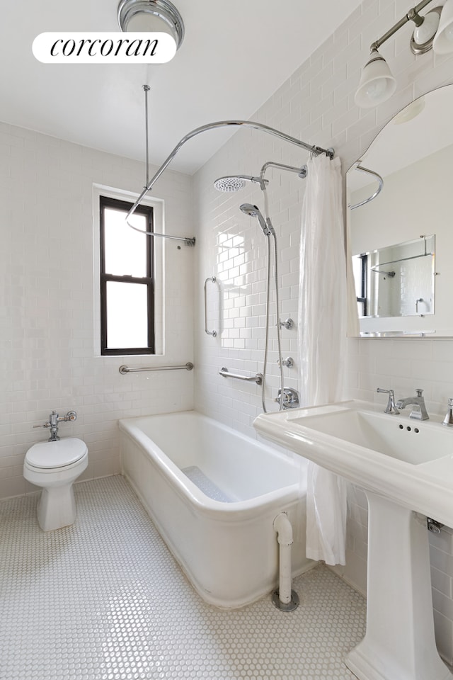 bathroom with tile patterned flooring, a sink, tile walls, and shower / bath combo with shower curtain