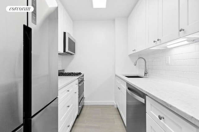 kitchen featuring tasteful backsplash, sink, light stone countertops, stainless steel appliances, and white cabinets