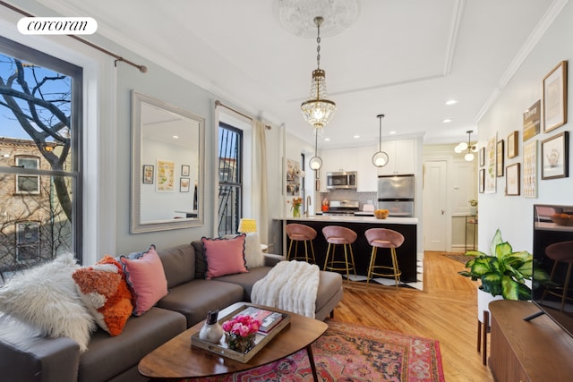 living room featuring an inviting chandelier, crown molding, and light hardwood / wood-style flooring