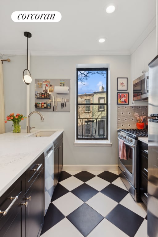 kitchen with pendant lighting, decorative backsplash, sink, crown molding, and stainless steel appliances