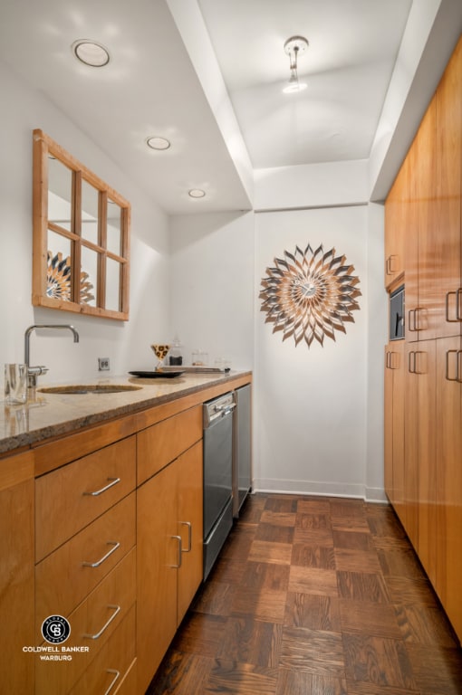 kitchen featuring stone counters, dishwasher, dark parquet floors, and sink