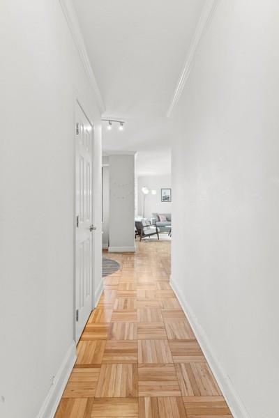 corridor with light parquet floors and crown molding