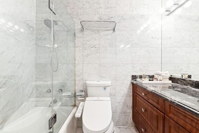 full bathroom with bath / shower combo with glass door, toilet, vanity, and tile walls