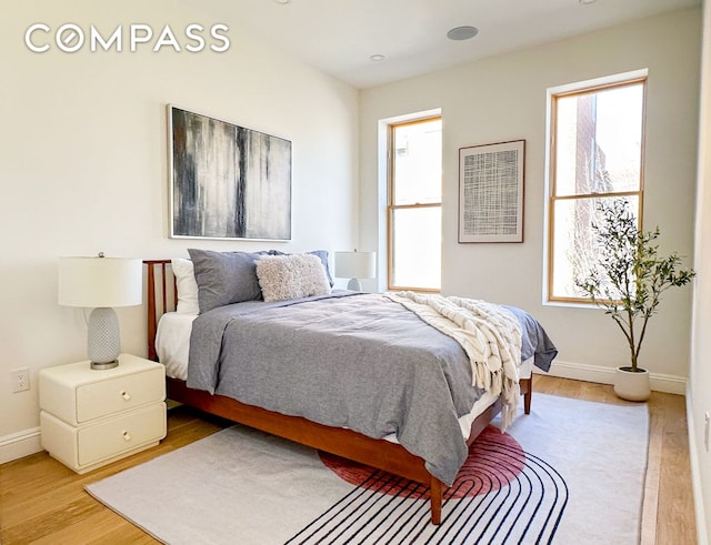 bedroom with light wood-type flooring, multiple windows, and baseboards