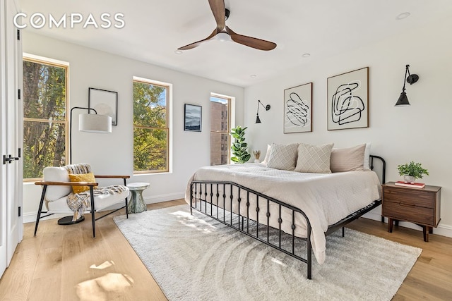 bedroom with light wood-style flooring, a ceiling fan, and baseboards