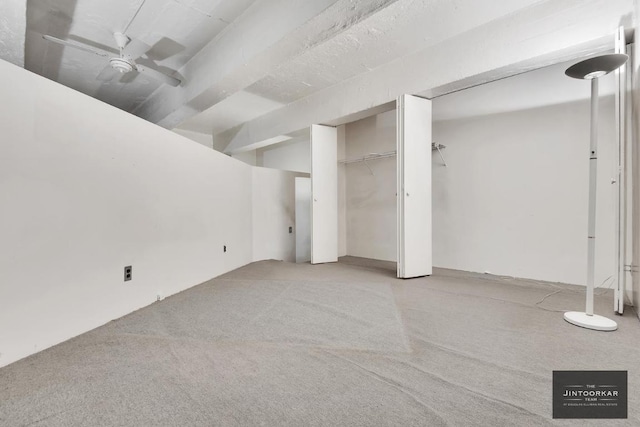 basement with ceiling fan and light colored carpet