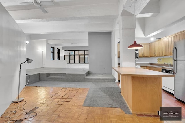 kitchen with pendant lighting, dishwasher, light brown cabinetry, sink, and stainless steel fridge