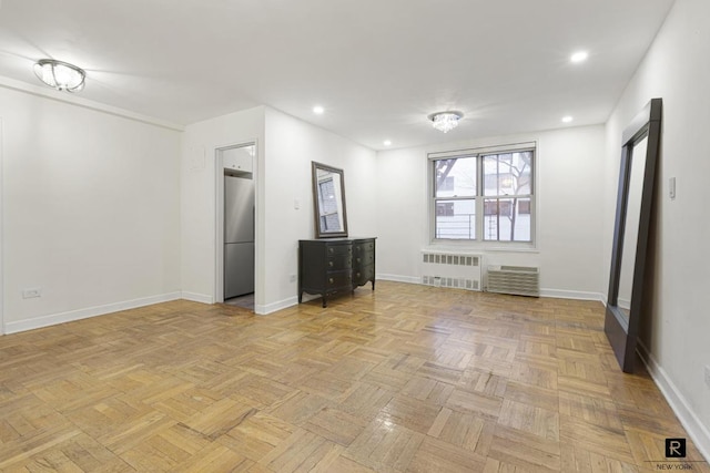 spare room featuring radiator and light parquet flooring