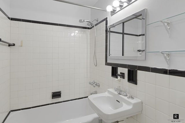 bathroom with tile walls, sink, and tiled shower / bath combo