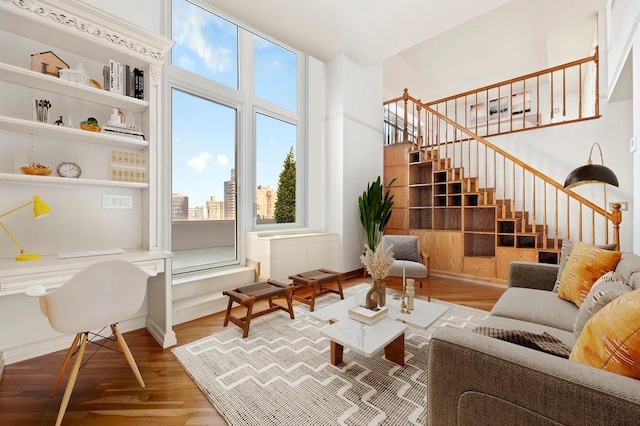 living area with stairs, a view of city, a healthy amount of sunlight, and wood finished floors