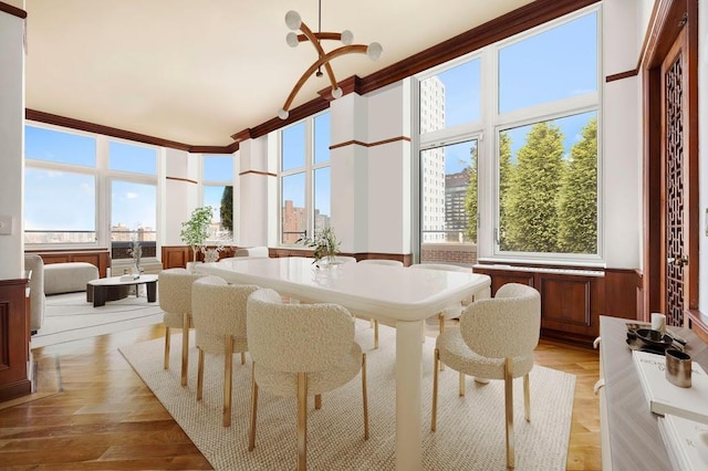 dining area featuring light wood-type flooring, an inviting chandelier, and a towering ceiling