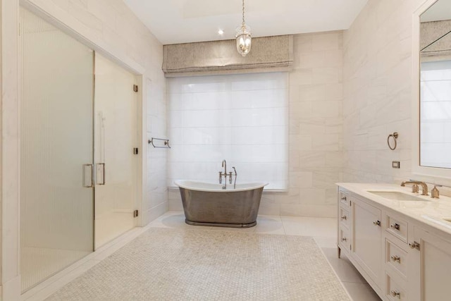 bathroom with tile patterned flooring, vanity, tile walls, and separate shower and tub