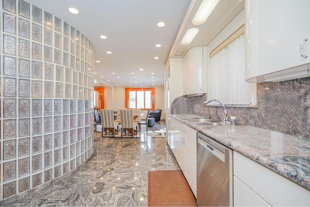 kitchen featuring dishwasher, sink, white cabinets, backsplash, and light stone countertops