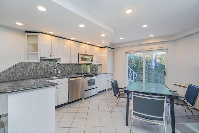 kitchen featuring sink, tasteful backsplash, light tile patterned floors, stainless steel appliances, and white cabinets