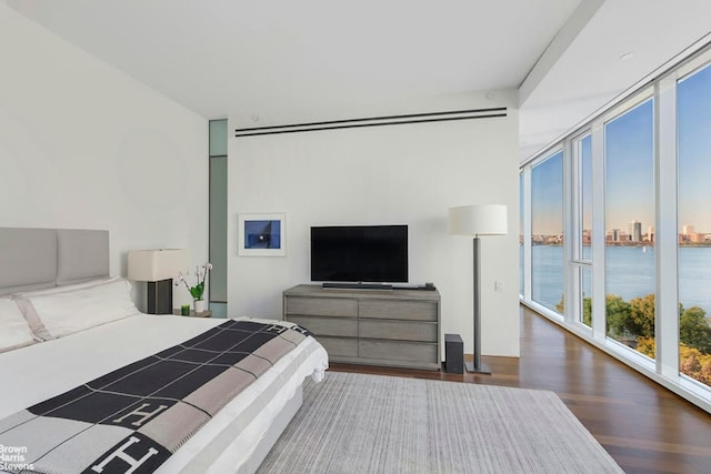 bedroom featuring dark hardwood / wood-style flooring, a wall of windows, and access to exterior