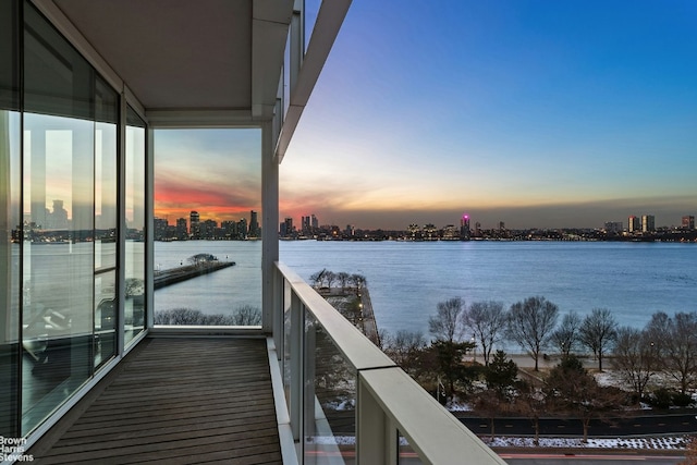 balcony at dusk featuring a water view