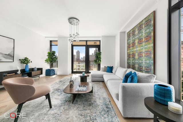 living room with french doors, an inviting chandelier, and light parquet flooring