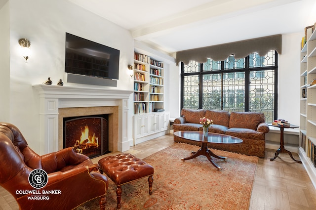 living room featuring a fireplace with flush hearth, beam ceiling, and built in features