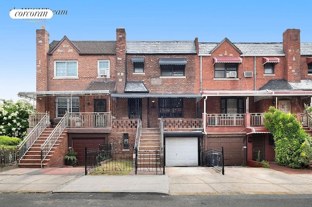 multi unit property featuring stairs, a garage, brick siding, and driveway