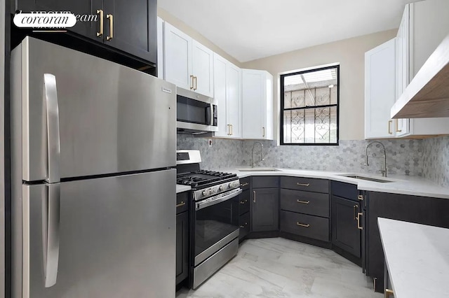 kitchen with a sink, stainless steel appliances, marble finish floor, white cabinetry, and tasteful backsplash