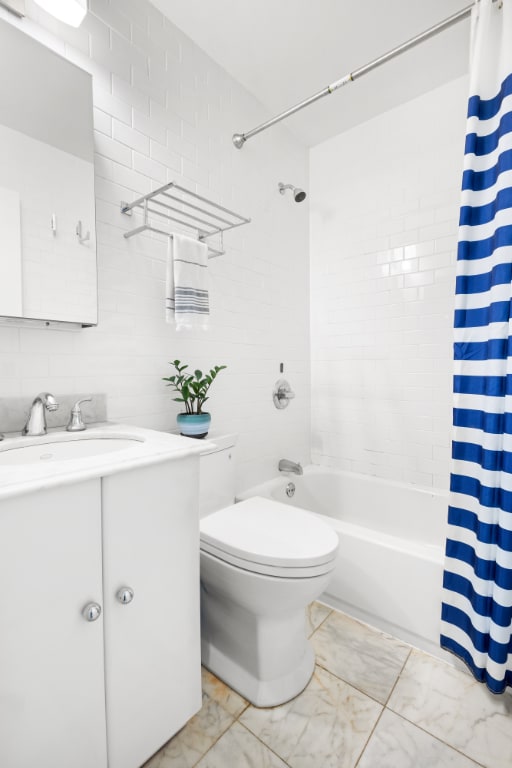 full bathroom with shower / tub combo with curtain, vanity, toilet, and tile walls