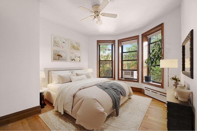 bedroom featuring ceiling fan, baseboard heating, cooling unit, and light hardwood / wood-style floors