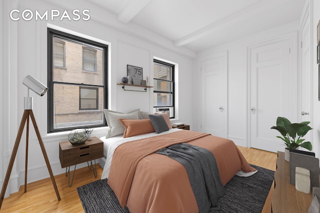 bedroom with baseboards, beam ceiling, and light wood-style floors