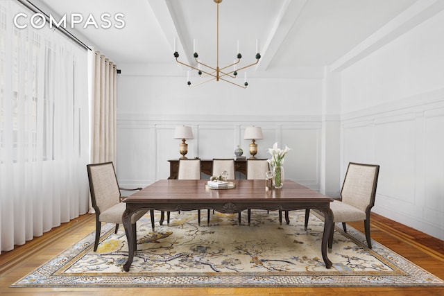 dining area with beam ceiling, a decorative wall, and a chandelier