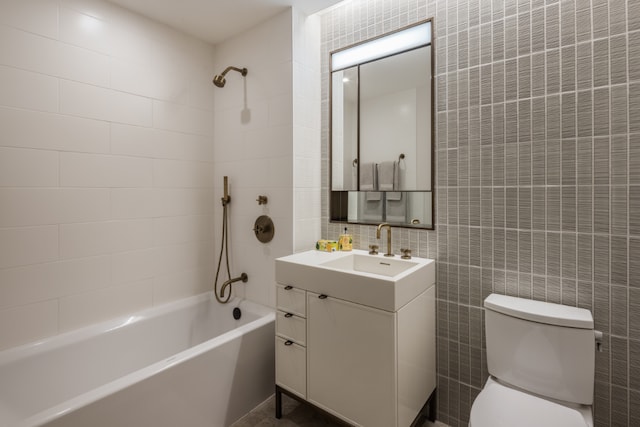 full bathroom featuring toilet, tile walls, vanity, and tiled shower / bath combo