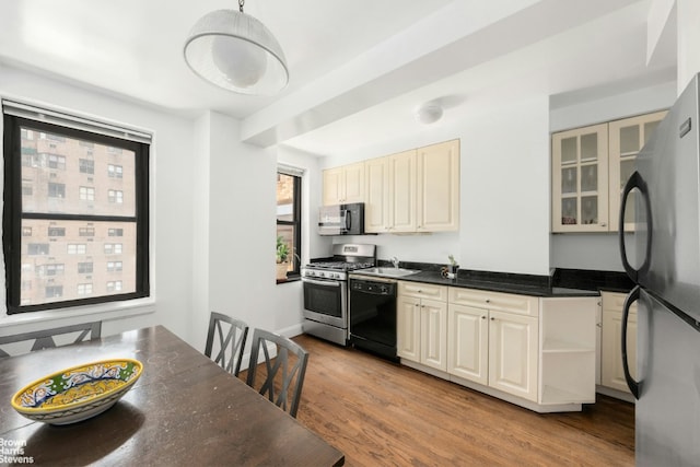 kitchen featuring black appliances, decorative light fixtures, sink, light hardwood / wood-style flooring, and cream cabinetry