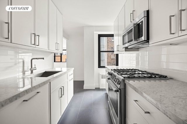 kitchen with light stone countertops, sink, white cabinets, and appliances with stainless steel finishes