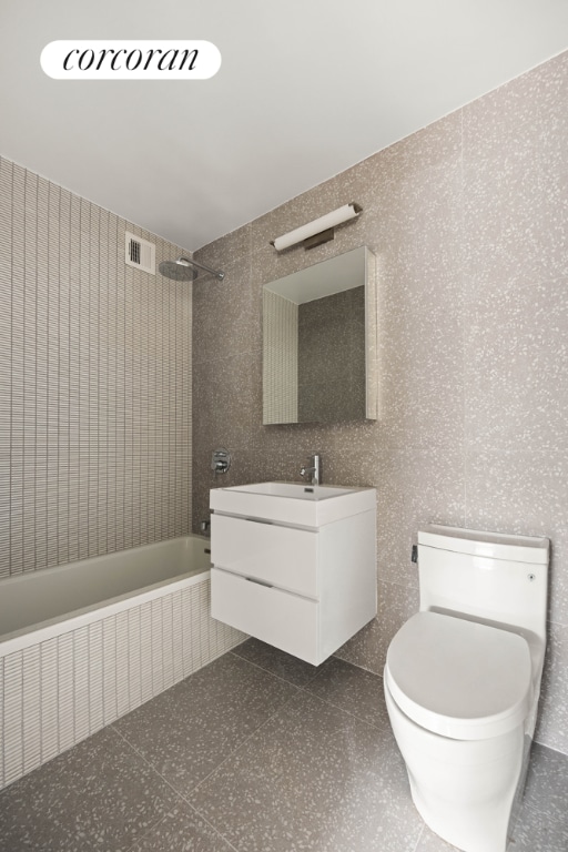 full bathroom with toilet, tiled shower / bath combo, tile walls, and vanity