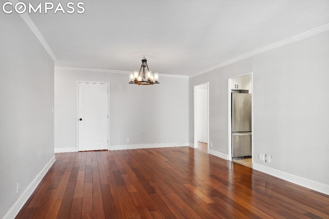 spare room with dark hardwood / wood-style flooring, ornamental molding, and an inviting chandelier