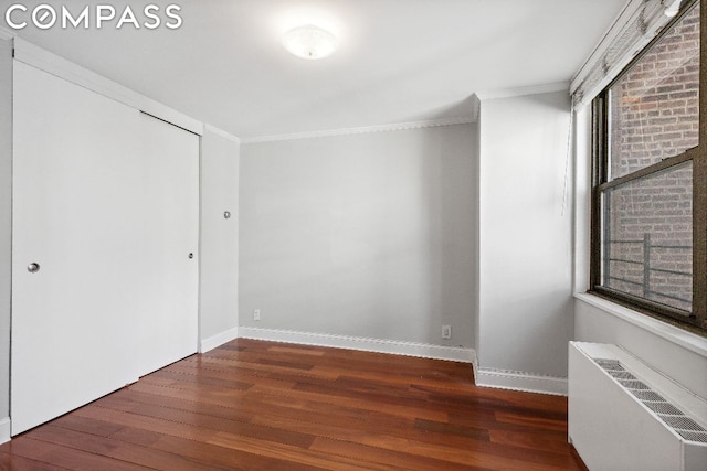 spare room with dark hardwood / wood-style floors, radiator heating unit, and crown molding