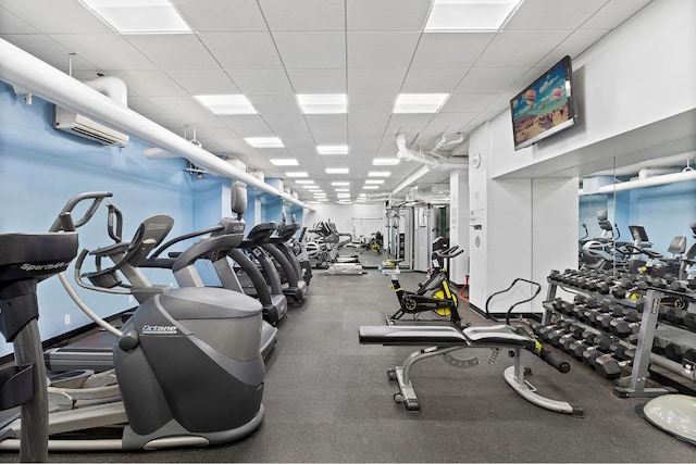 gym with a paneled ceiling and a wall mounted air conditioner