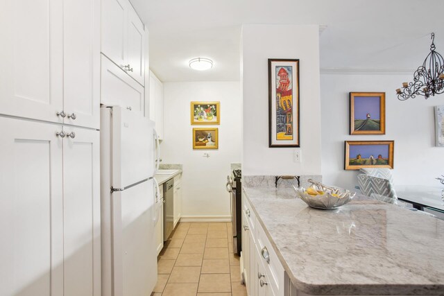 kitchen with light stone counters, white fridge, and white cabinets