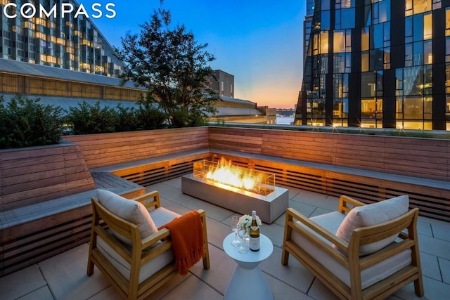 patio terrace at dusk with an outdoor living space with a fire pit