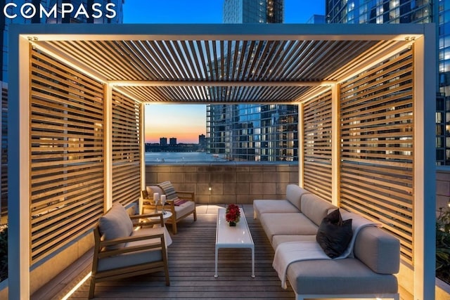 deck at dusk with an outdoor hangout area and a pergola