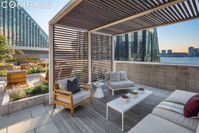 patio terrace at dusk with an outdoor hangout area, a pergola, and a water view