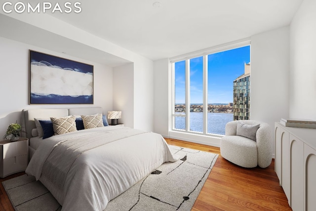 bedroom with a water view and hardwood / wood-style flooring