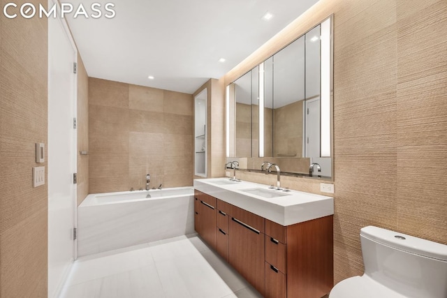 bathroom featuring toilet, vanity, tile walls, tile patterned floors, and a bath