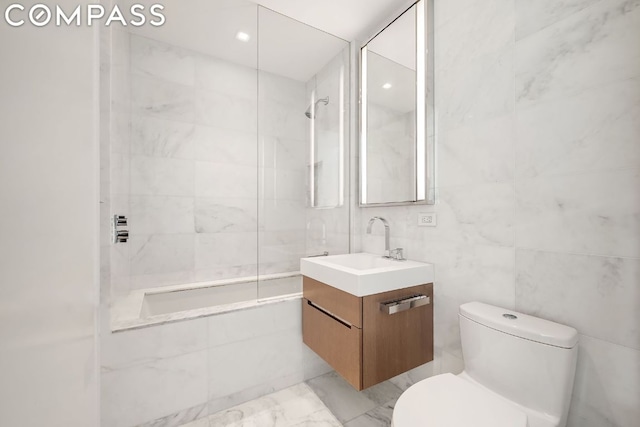 full bathroom featuring toilet, bathing tub / shower combination, tile walls, and vanity