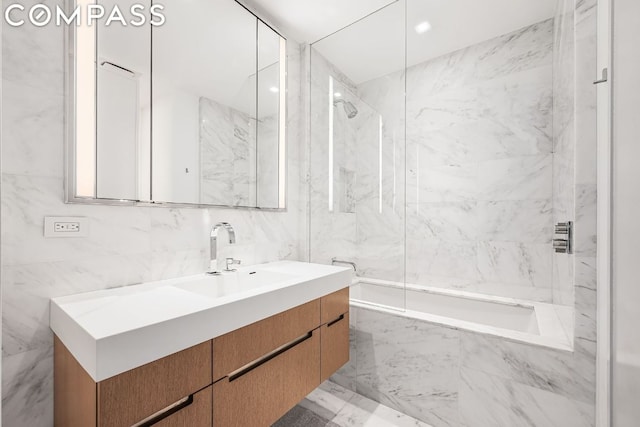 bathroom featuring tile walls, tiled shower / bath combo, and vanity