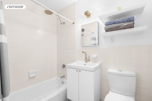 full bathroom with tile walls, toilet, vanity, and shower / tub combo