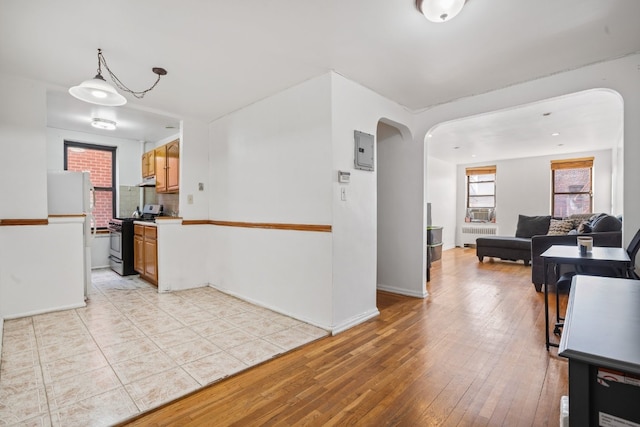 kitchen with radiator, cooling unit, white refrigerator, light hardwood / wood-style floors, and gas range