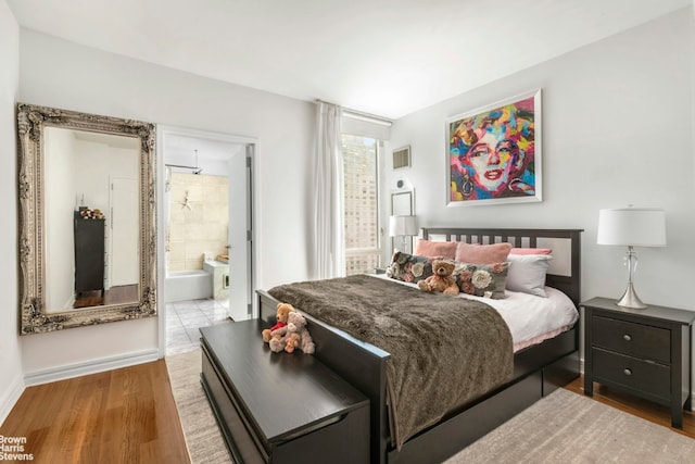 bedroom with light wood-type flooring and ensuite bathroom