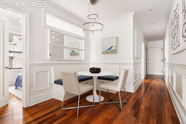 dining space with dark hardwood / wood-style floors, crown molding, and a chandelier