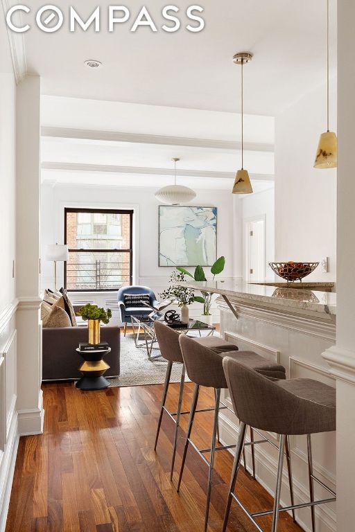 kitchen with hanging light fixtures, light stone countertops, dark hardwood / wood-style floors, and a kitchen breakfast bar