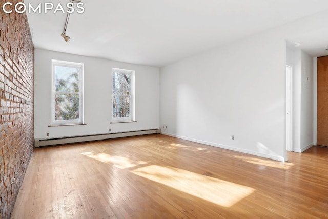 unfurnished room featuring light wood-type flooring, track lighting, and a baseboard radiator