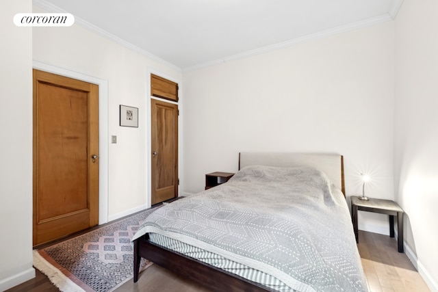 bedroom featuring ornamental molding, visible vents, baseboards, and wood finished floors